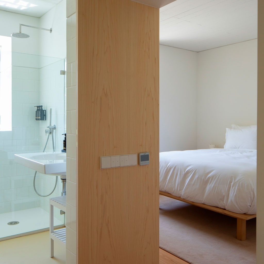 uma porta de madeira leva a um quarto com uma cama e uma pia