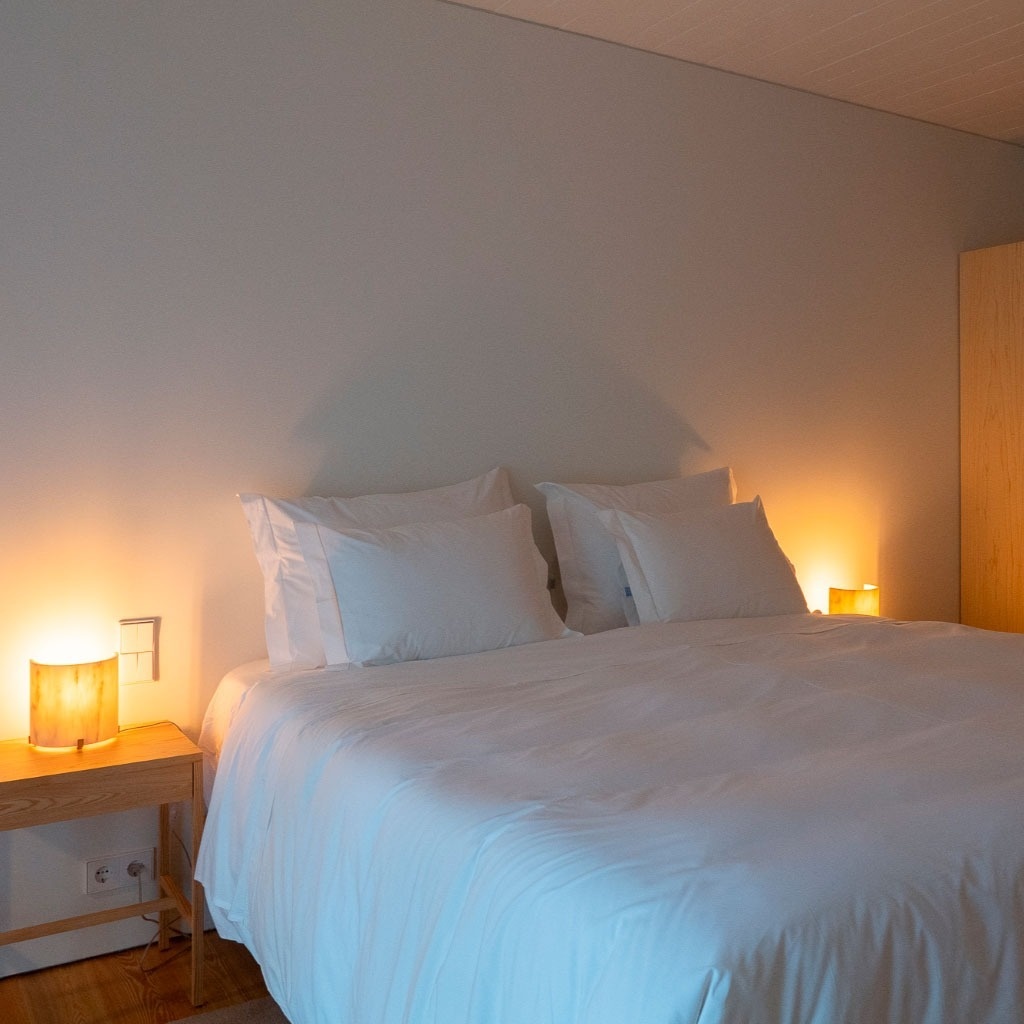 uma cama com cobertor branco e travesseiros em um quarto