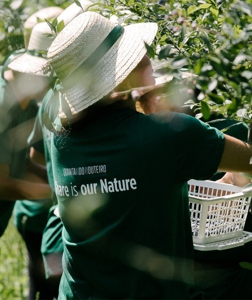 um homem com um chapéu de palha e uma camisa verde que diz " aqui é a nossa natureza "