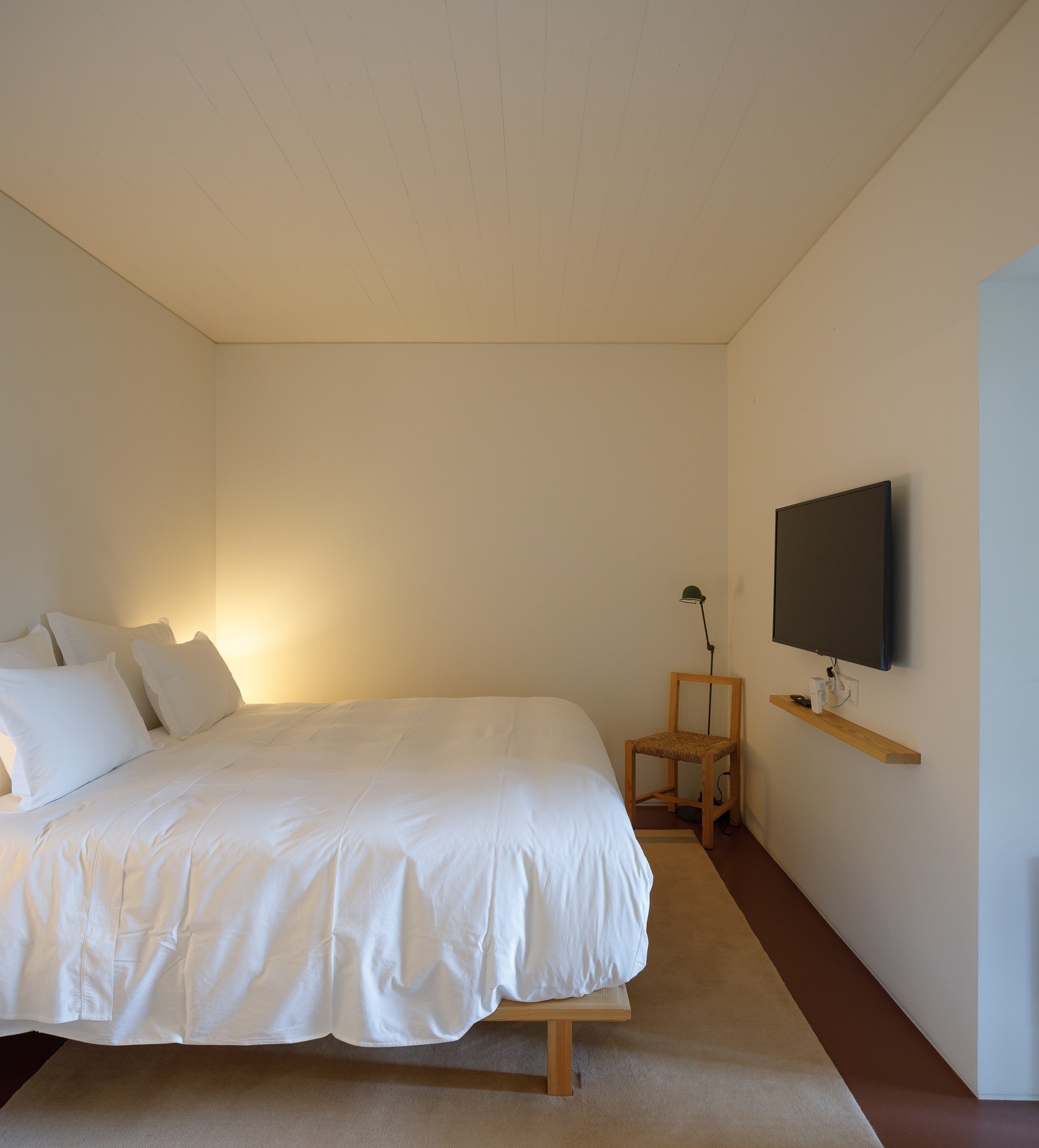 um quarto com cama e televisão na parede