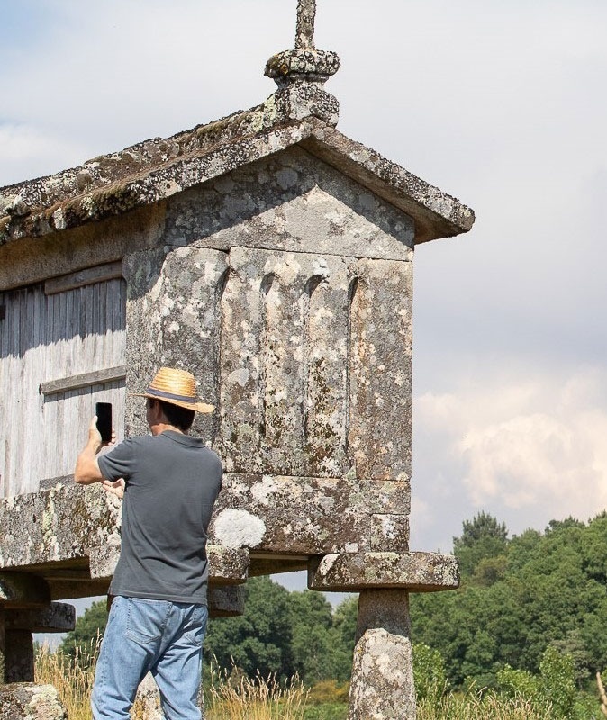 um homem em um chapéu de palha está tirando uma foto de um edifício de pedra