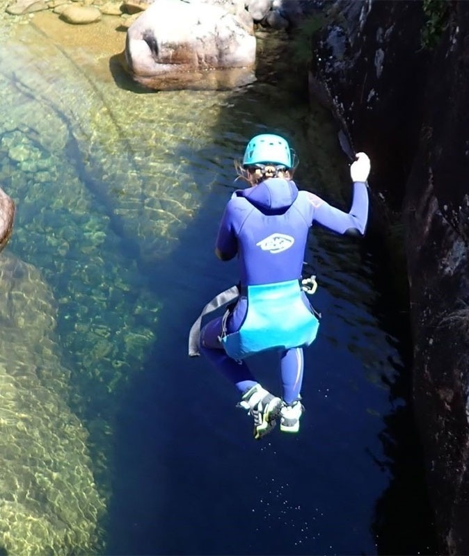 uma pessoa vestindo uma roupa de neoprene e um capacete salta para a água