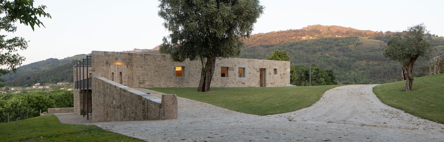 uma estrada de terra que leva a uma casa de pedra