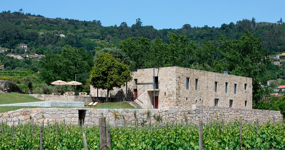uma grande casa de pedra com uma piscina ao fundo