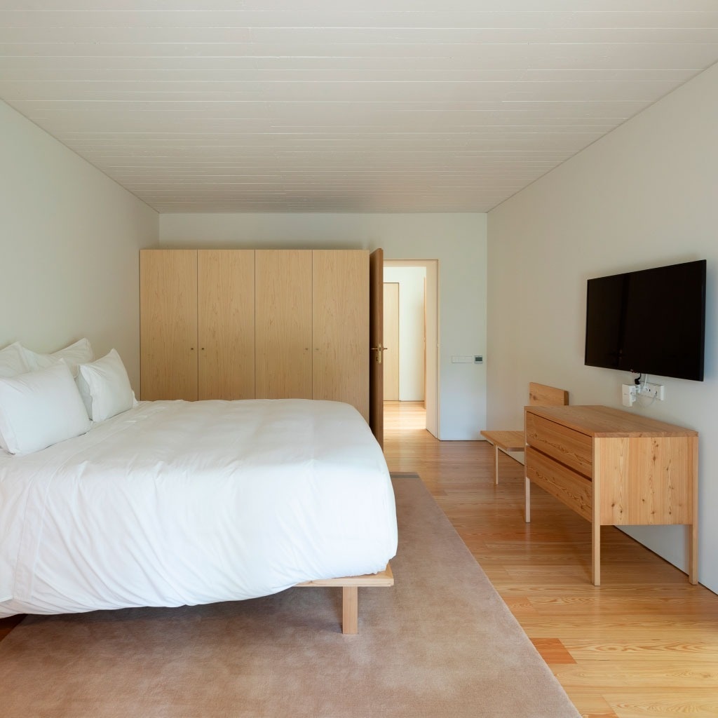 um quarto com cama e televisão na parede