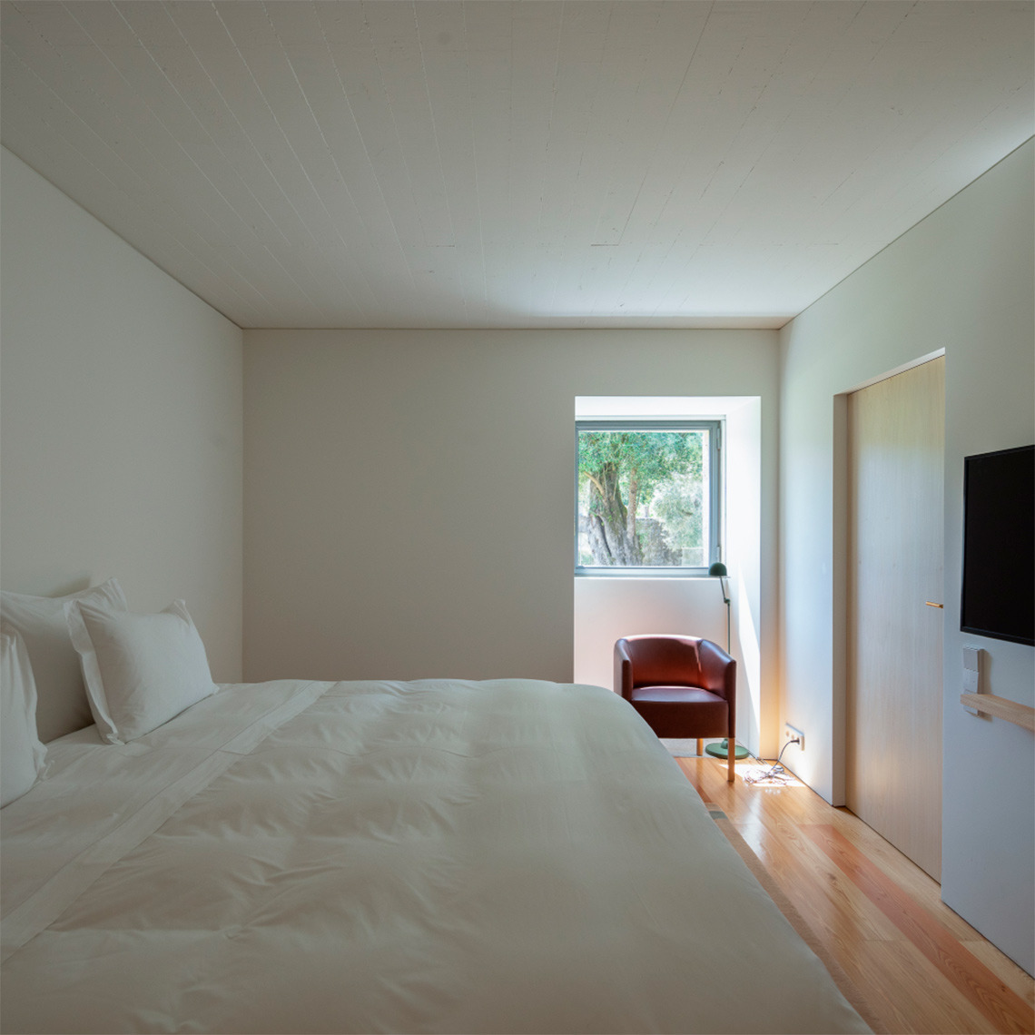 Habitación acogedora en Quinta do Outeiro con cama doble y silla de lectura junto a la ventana.