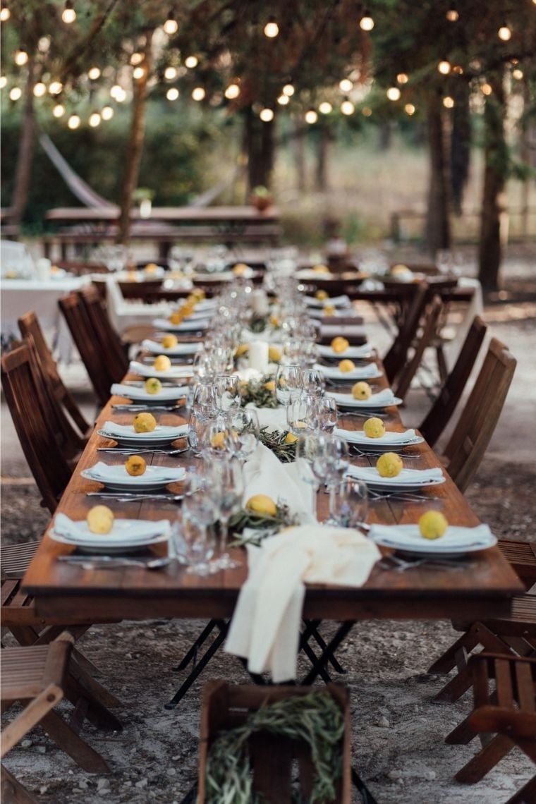 a long wooden table with plates glasses and lemons on it