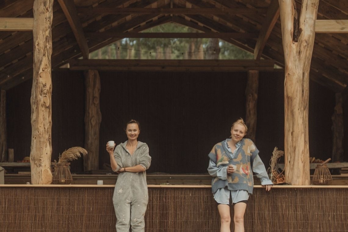 two women standing next to each other one holding a cup of coffee
