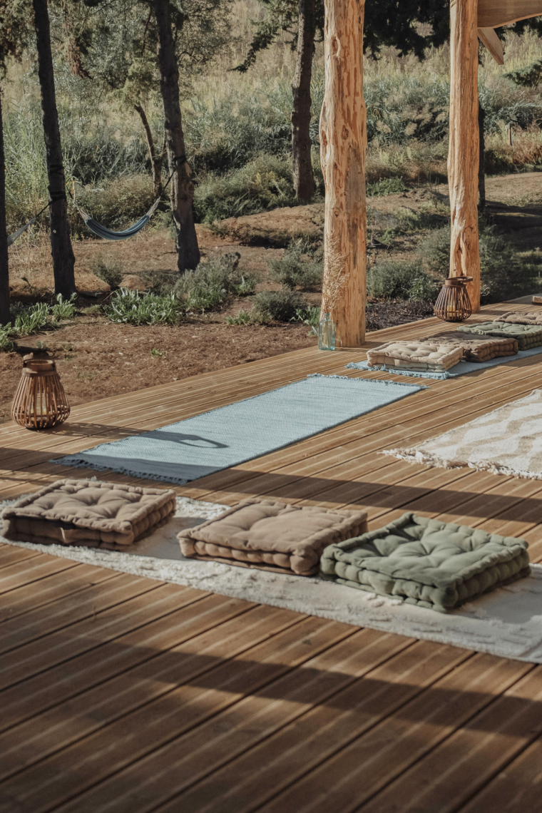 a wooden deck with yoga mats and pillows on it