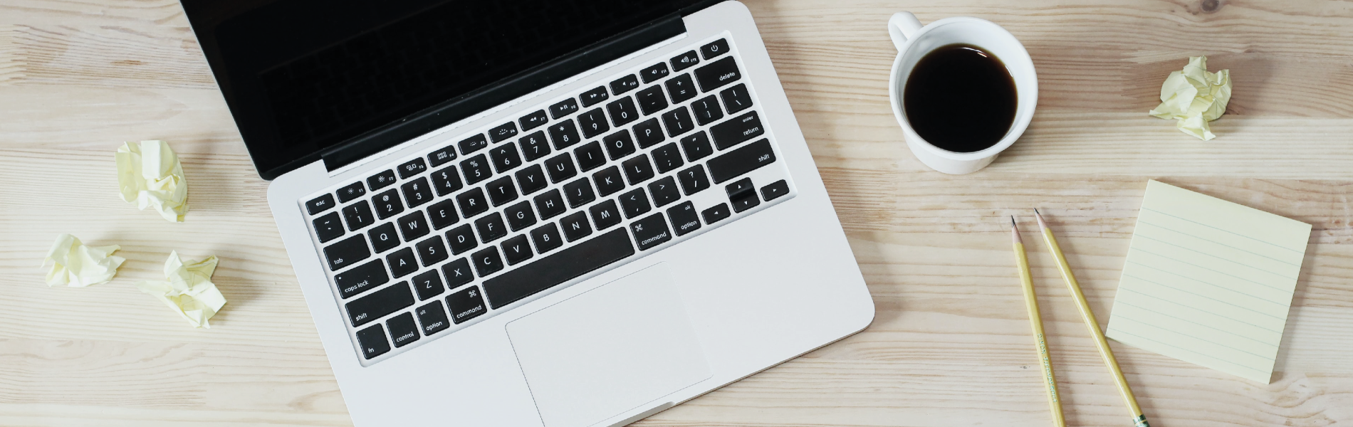 a laptop sits on a wooden desk next to a cup of coffee