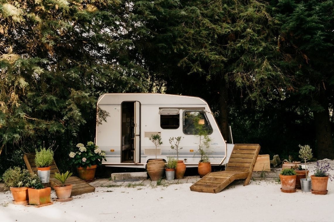 a white camper is parked in a lush green forest