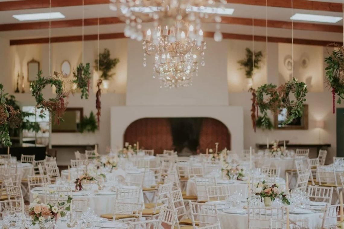 tables and chairs set up for a wedding reception with flowers hanging from the ceiling