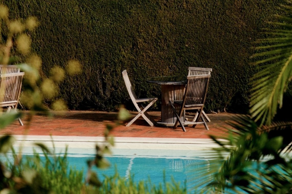 a table and chairs sit near a swimming pool