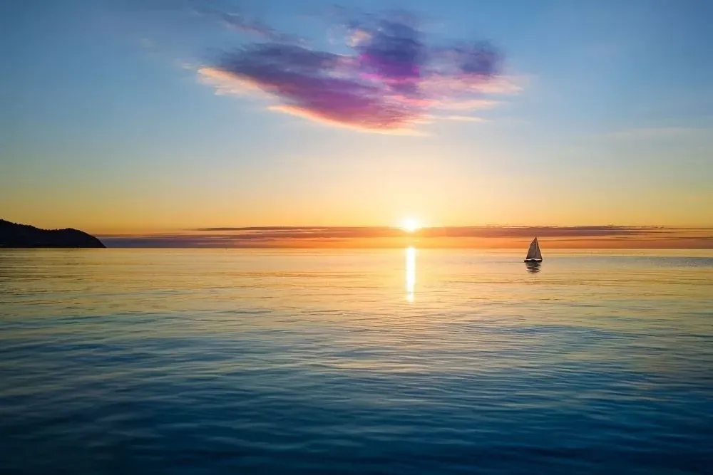 R2 Hoteles: Corporativa - Yate solitario al atardecer en el mar.