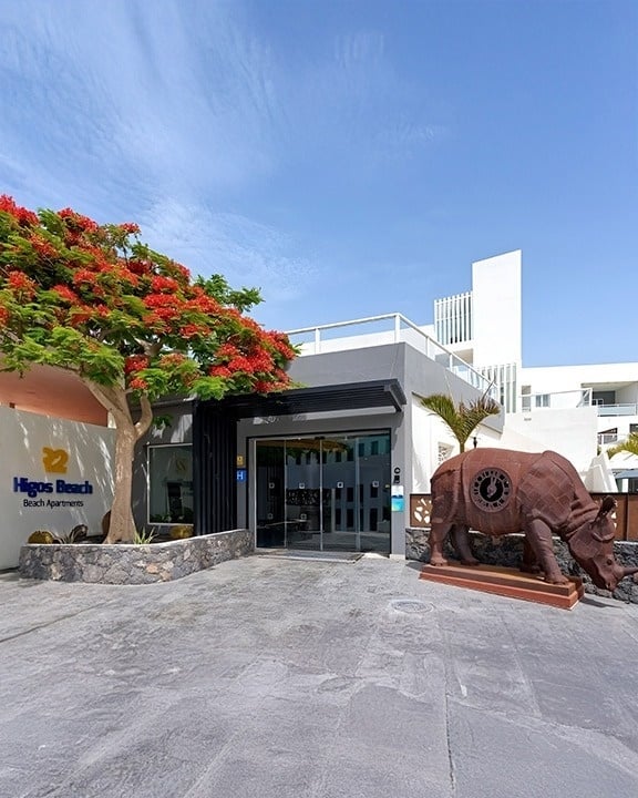 a large hotel with a swimming pool surrounded by chairs and umbrellas