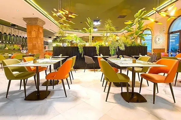 R2 Hotels: Modernes Restaurant mit grünen und orangen Stühlen.