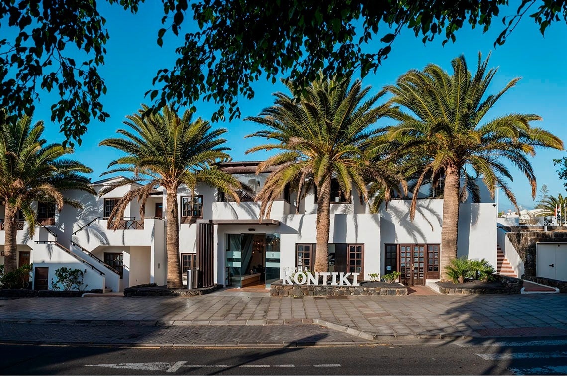 R2 Bahía Kontiki Beach Apartments: fachada blanca con palmeras y cartel de bienvenida.