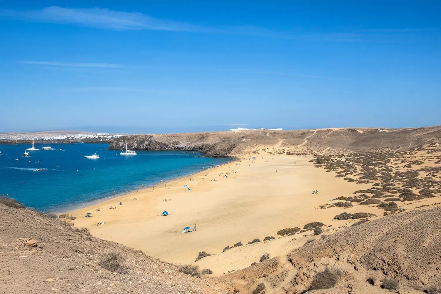 R2 Hotels: Spiaggia dorata e acque turchesi con barche a vela.