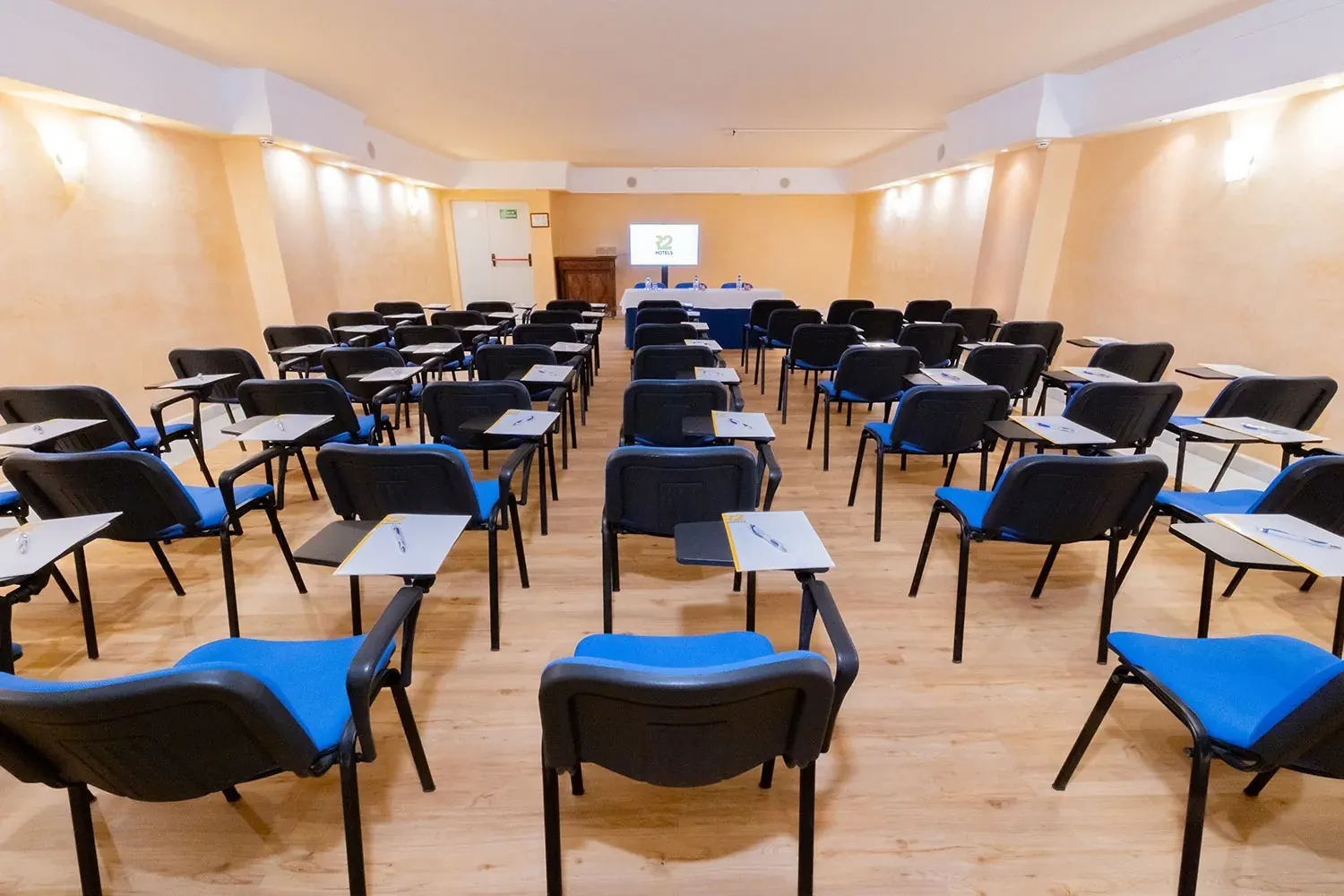 R2 Hotels Konferenzraum für Unternehmen mit blauen Stühlen und Tischen.