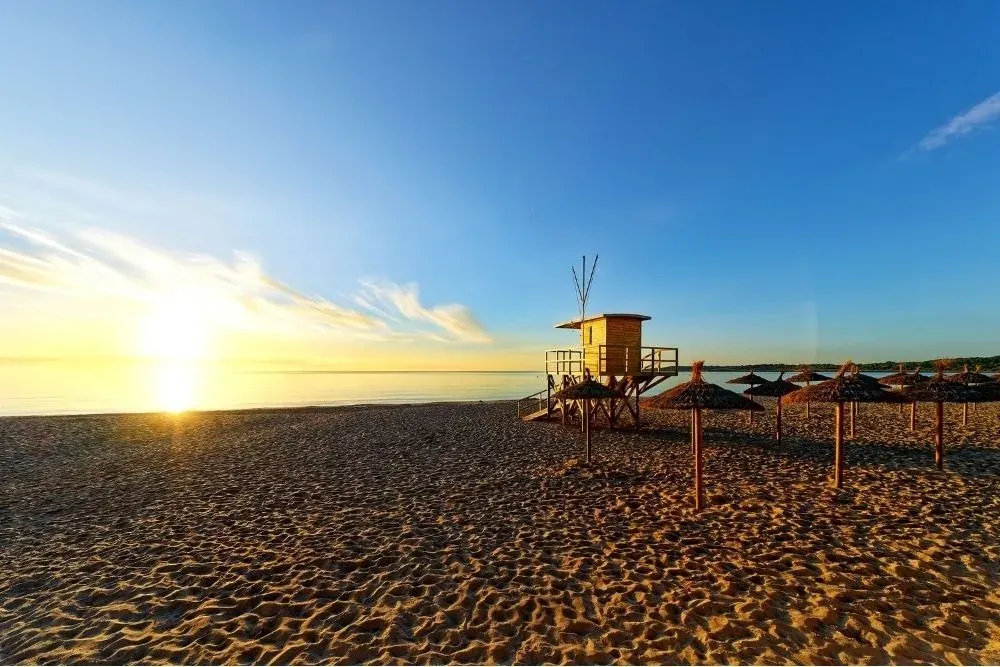 R2 Hoteles: Playa al amanecer con puesto de socorrista y sombrillas.