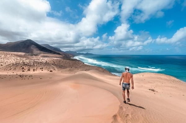 an aerial view of a beach with mountains in the background