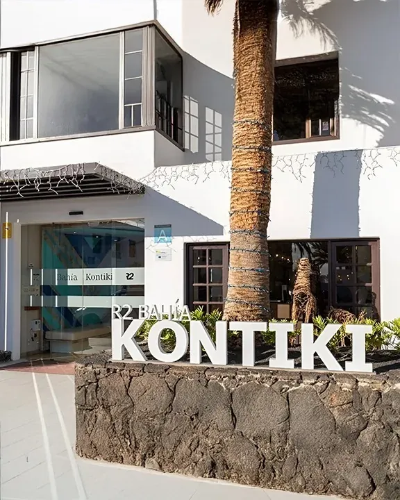 R2 Bahía Kontiki Strandapartments: Weiße Schrift auf Steinmauer vor dem Hotel.