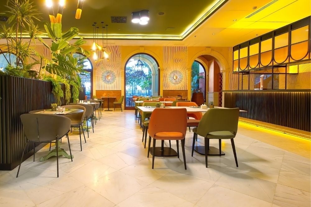 R2 Río Calma Hotel Fuerteventura: Essbereich mit stilvollen Tischen, Stühlen, Pflanzen und warmem Licht.