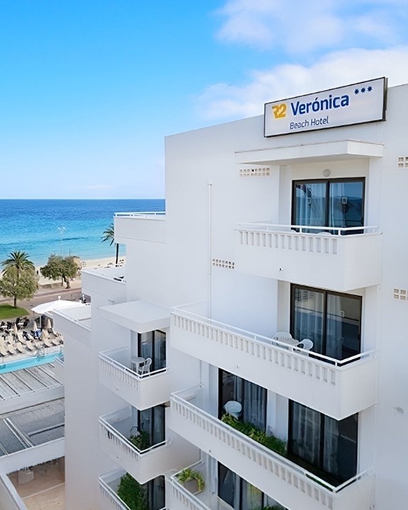 a large hotel with a swimming pool surrounded by chairs and umbrellas