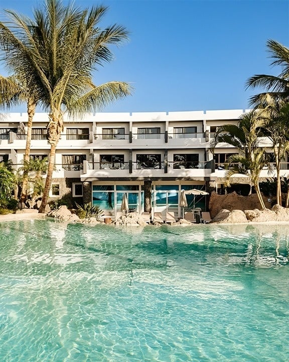 a large hotel with a swimming pool surrounded by chairs and umbrellas