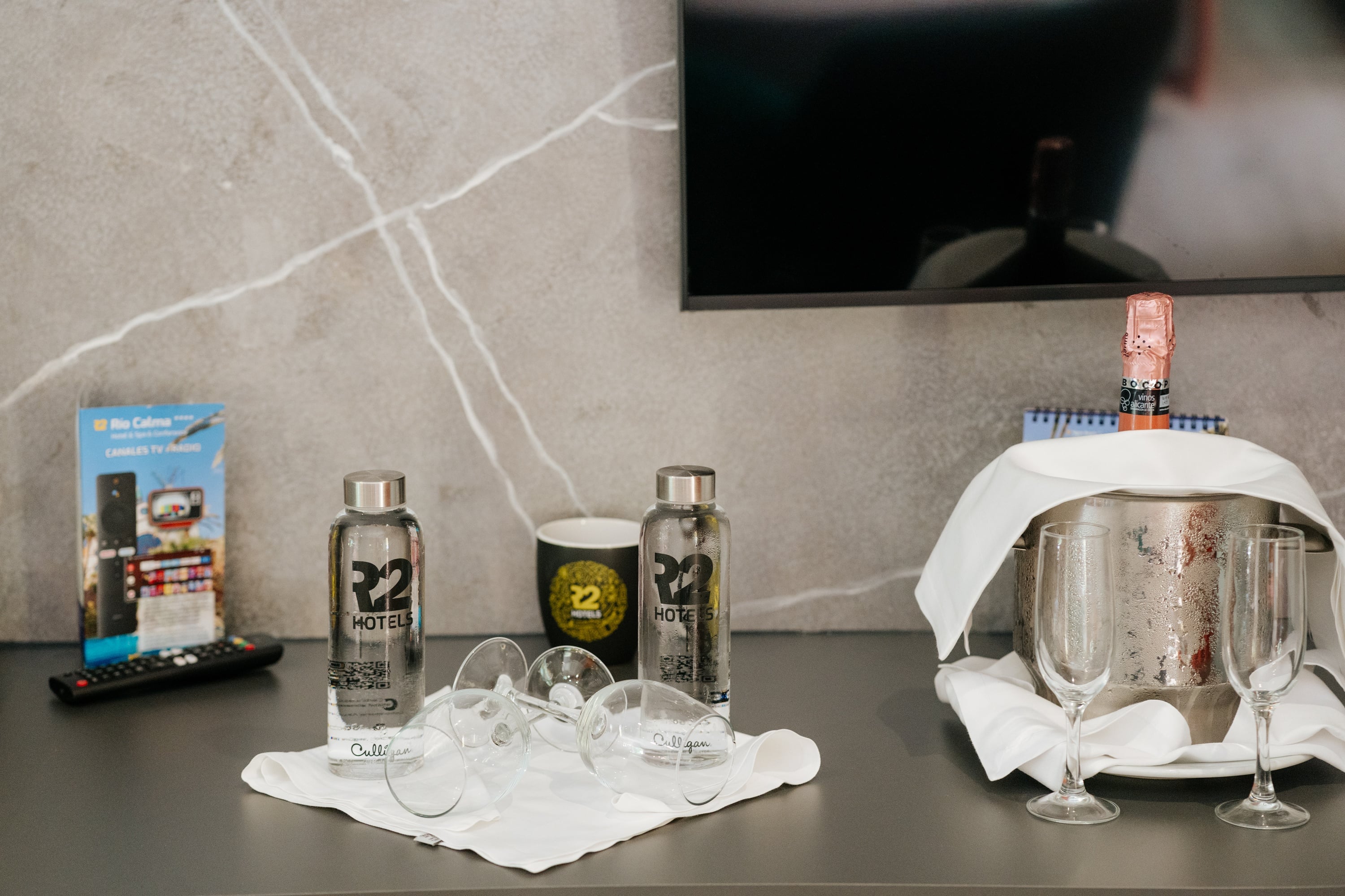 R2 Hôtels: Bouteilles d'eau offertes et champagne dans un seau à glace.