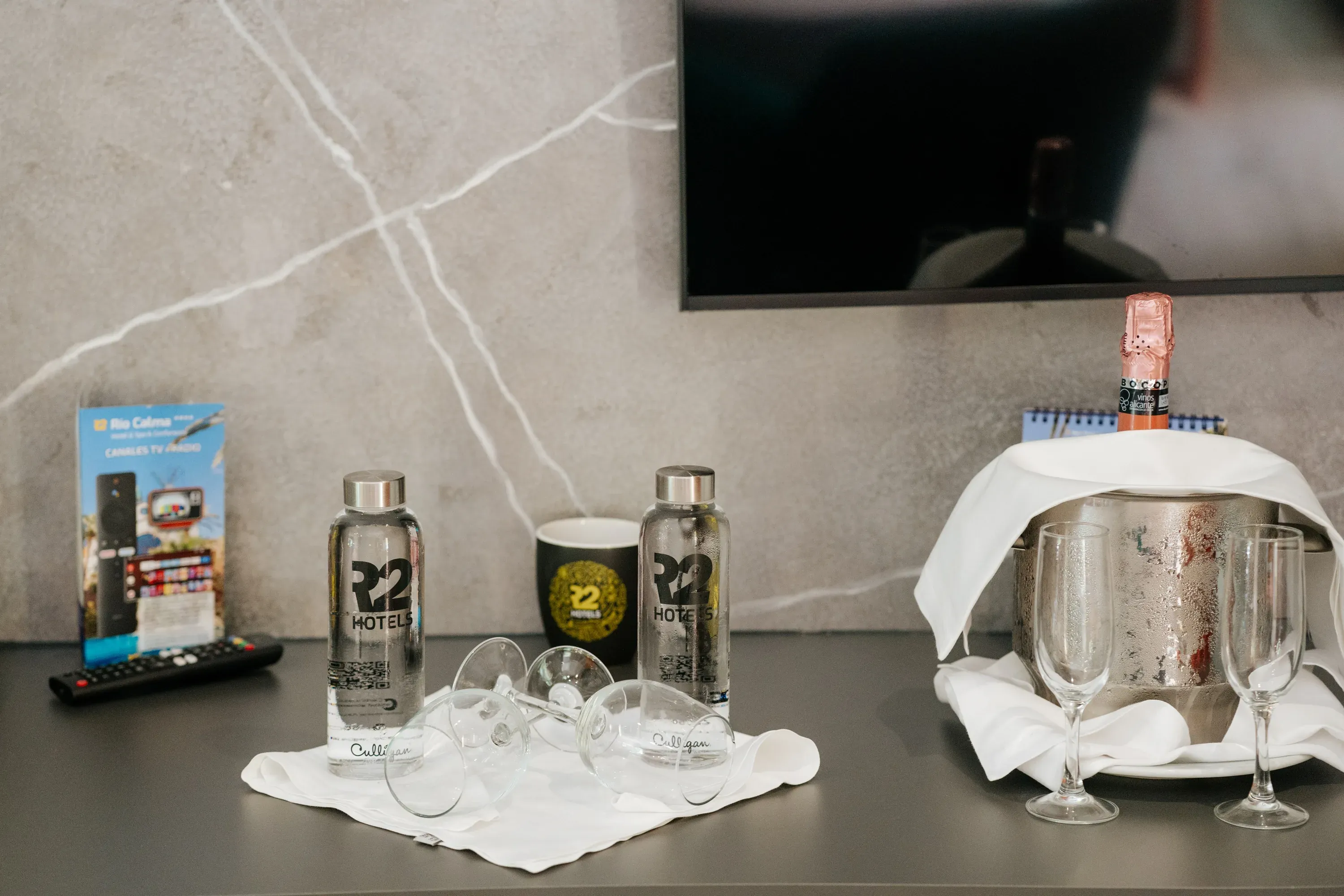 R2 Hôtels: Bouteilles d'eau offertes et champagne dans un seau à glace.