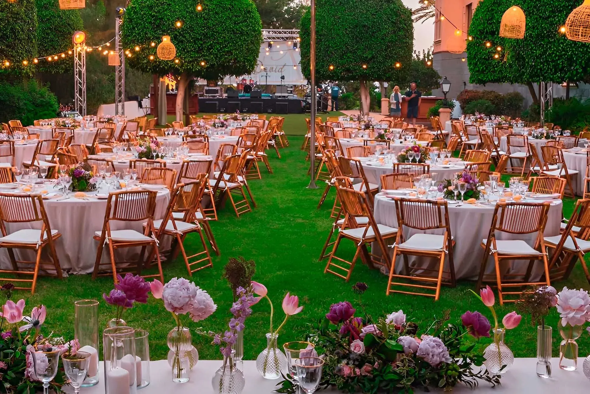 R2 Hoteles: Corporativa, montaje de evento exterior elegante con mesas y flores.