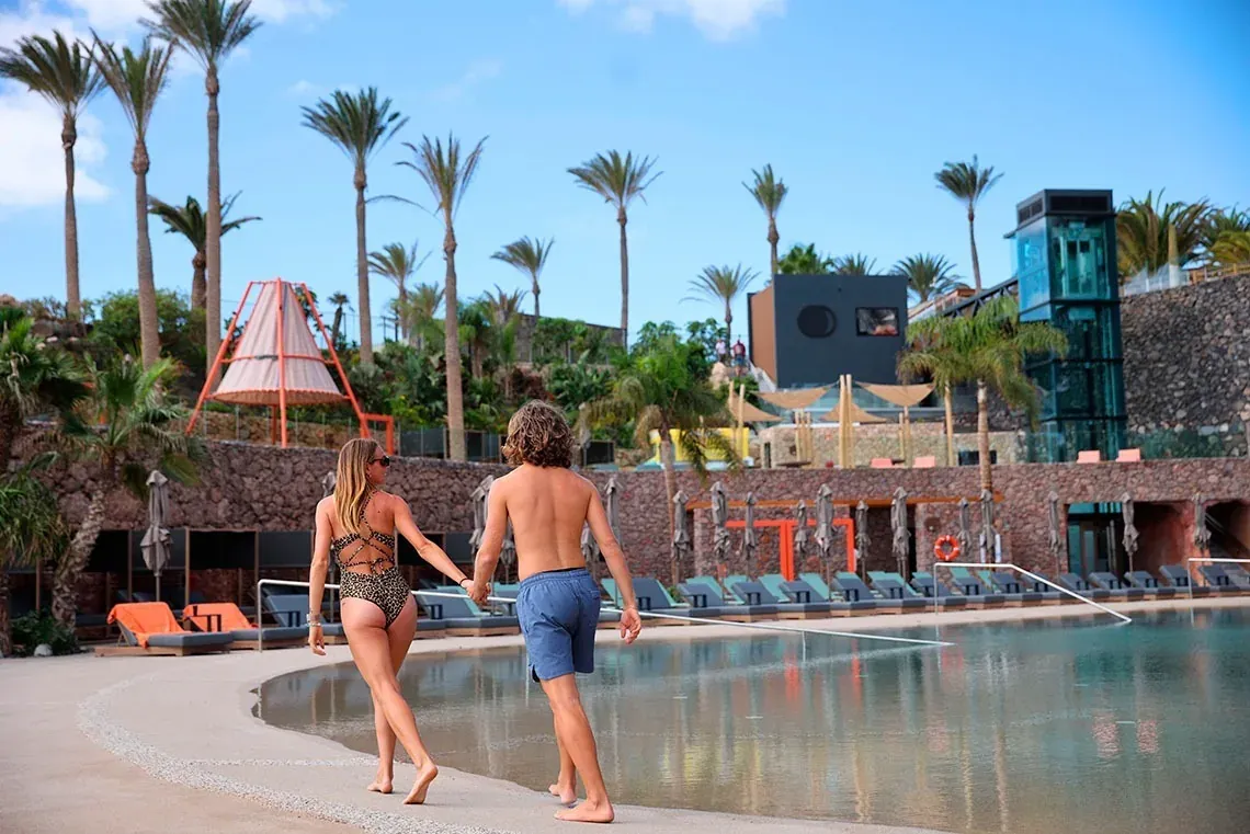 Pareja relajándose en R2 Hoteles: Corporativa, con vistas a la piscina.
