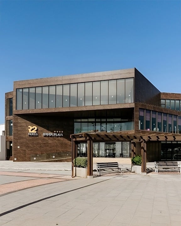 a large hotel with a swimming pool surrounded by chairs and umbrellas