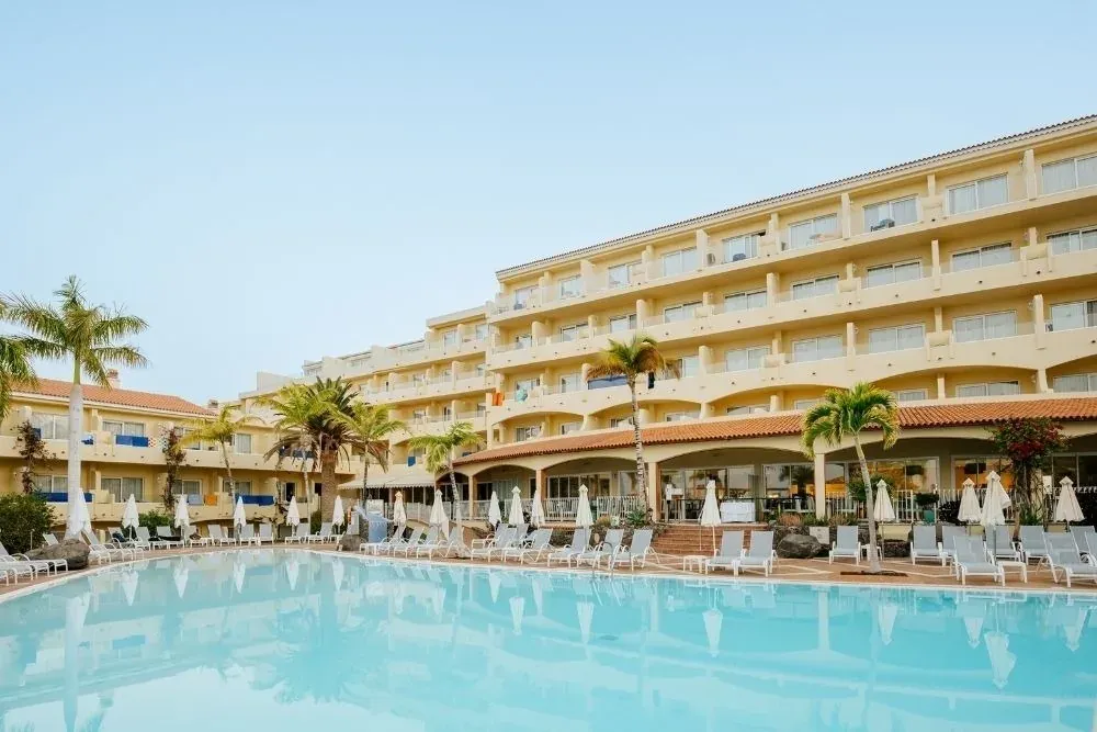 R2 Hoteles: Piscina y edificio principal con palmeras. Relájate y disfruta.