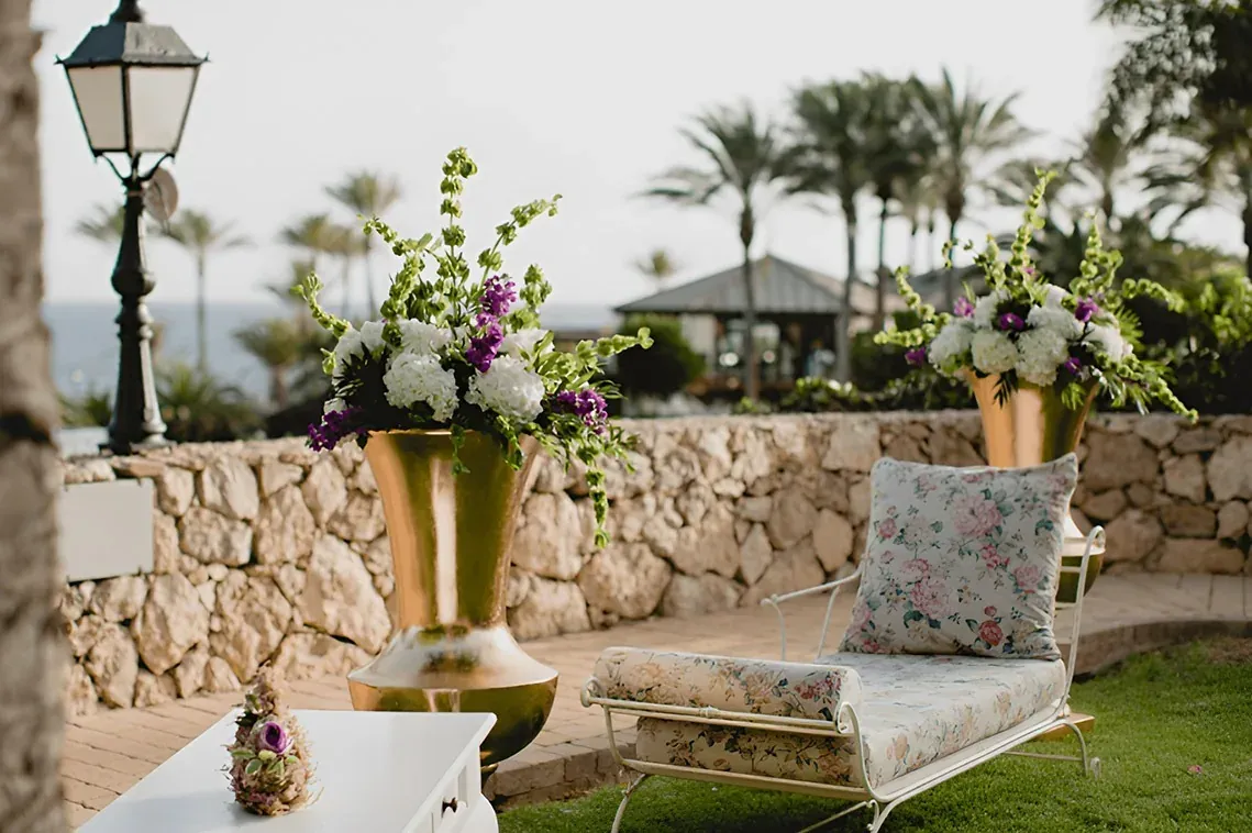 R2 Hoteles: Corporativa, diván floral junto a macetones en patio.