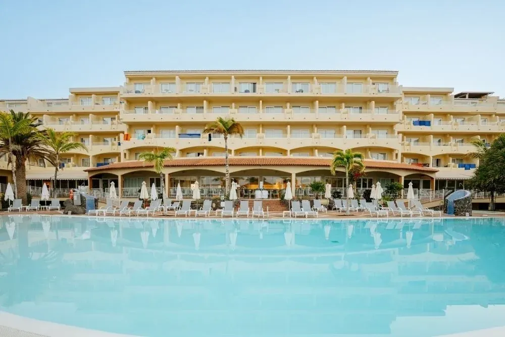 R2 Hoteles: Corporativa. Piscina y hotel con palmeras.