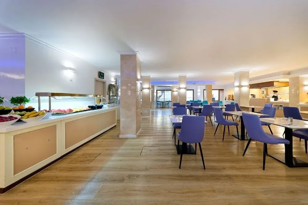R2 Hoteles: Corporativa – Buffet desayuno con mobiliario moderno y asientos morados.
