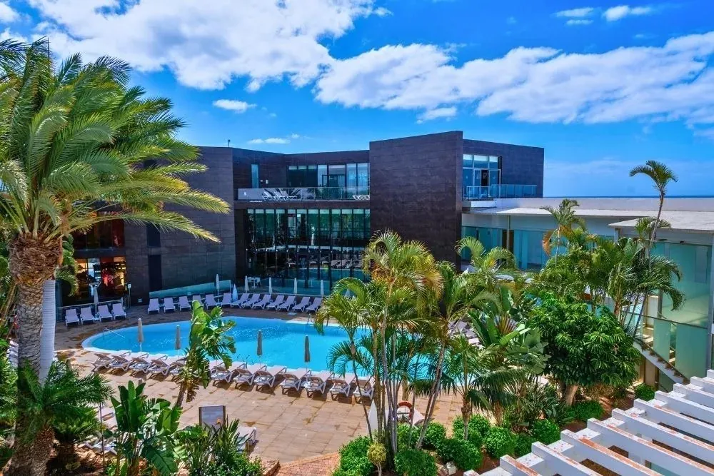 R2 Hoteles: Resort moderno con piscina, palmeras y sol.