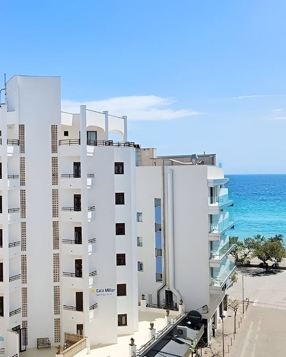 a large hotel with a swimming pool surrounded by chairs and umbrellas