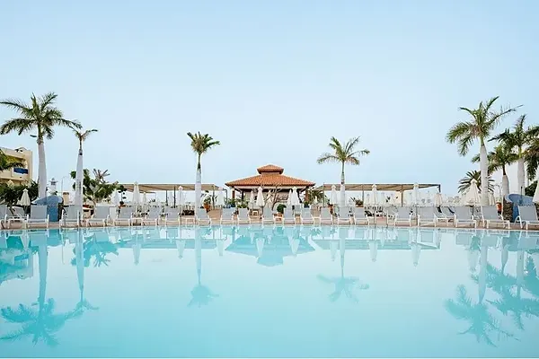 R2 Hoteles: Piscina y palmeras con tumbonas, ideal para vacaciones.