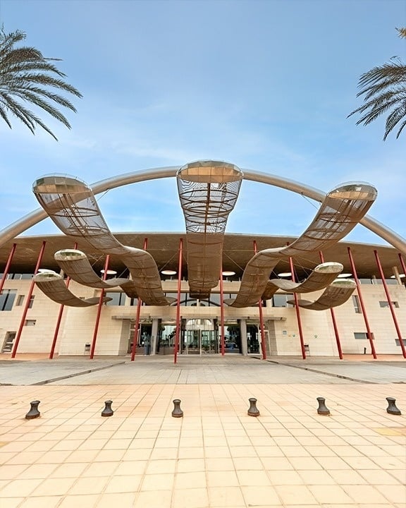 a large hotel with a swimming pool surrounded by chairs and umbrellas