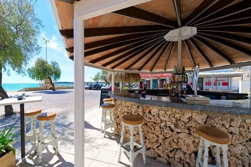 Bar corporativo R2 Hoteles junto al mar con taburetes y vista a la playa.