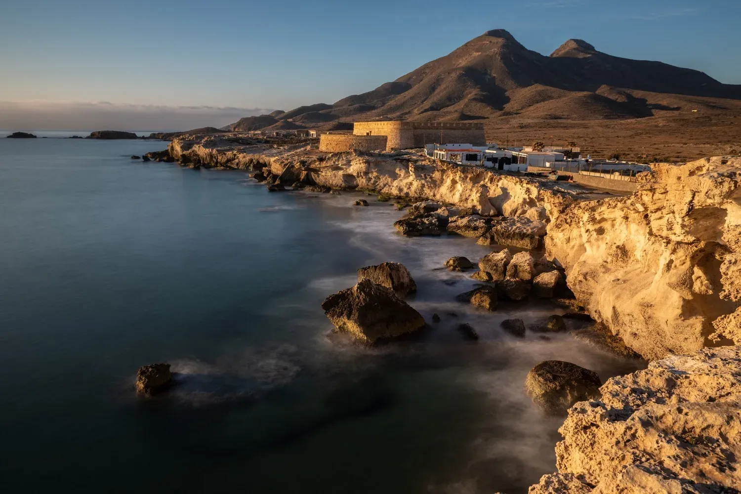 R2 Hotels: Costa rocciosa e mare blu sotto un cielo limpido.