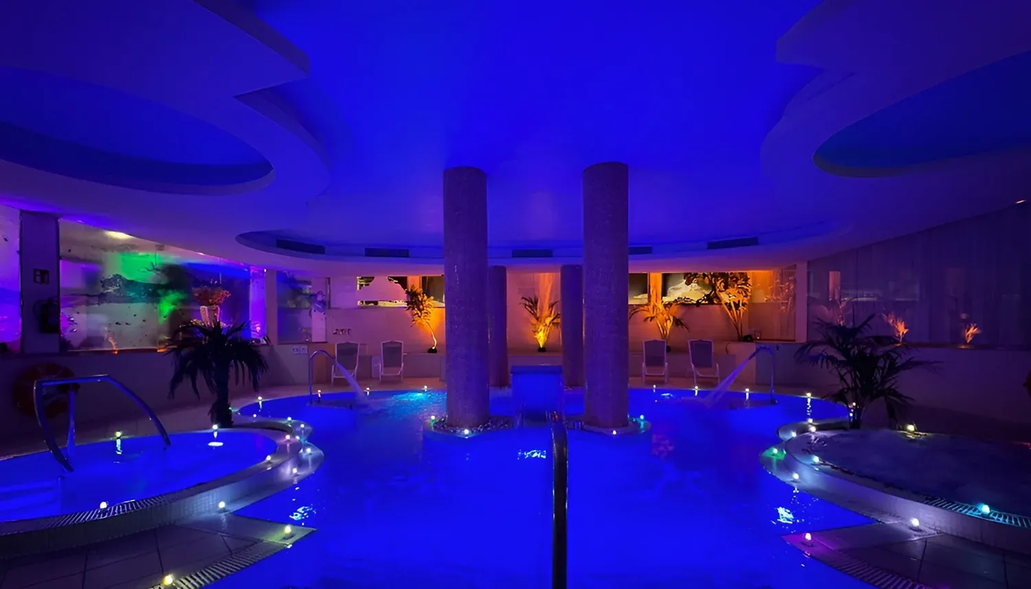 Spa intérieur avec piscine bleue, R2 Hôtels: Corporate, lumières et palmiers.