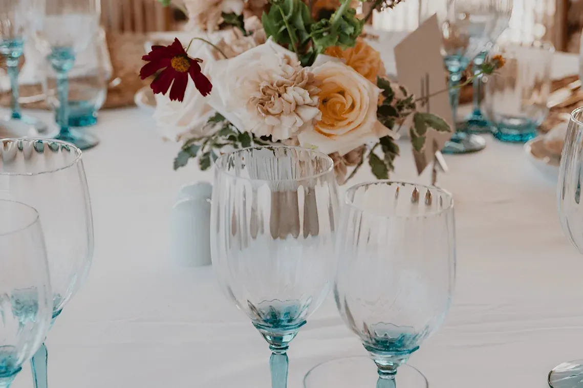 Mesa para eventos corporativos R2 Hoteles con copas de cristal y flores.