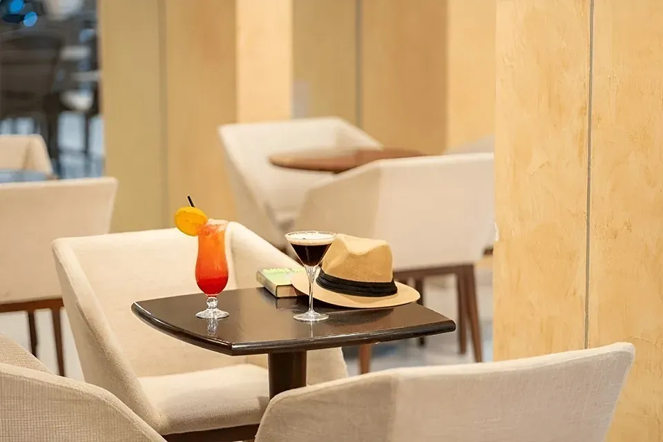 R2 Hotels: Cocktail tropicale e cappello su un tavolino da caffè.