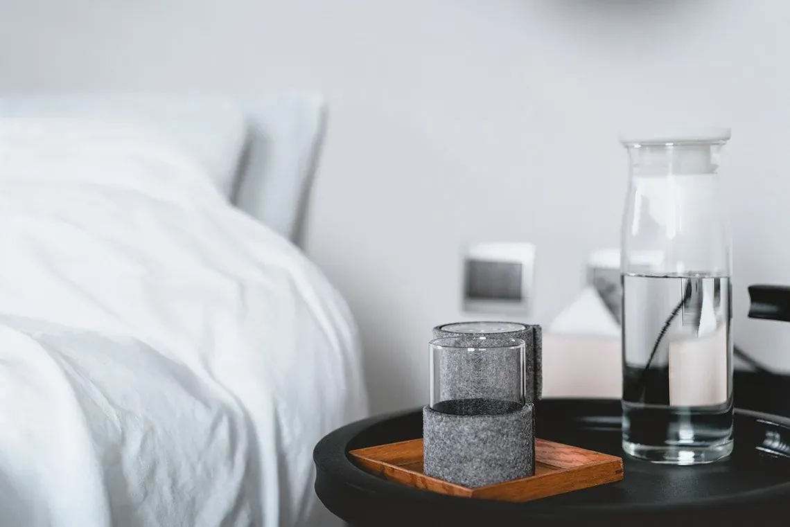 R2 Hoteles: Corporativa - Zwei Gläser und Wasserflasche auf Nachttisch neben dem Bett.