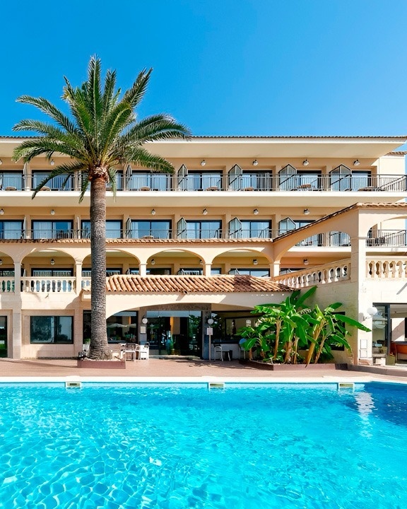 a large hotel with a swimming pool surrounded by chairs and umbrellas