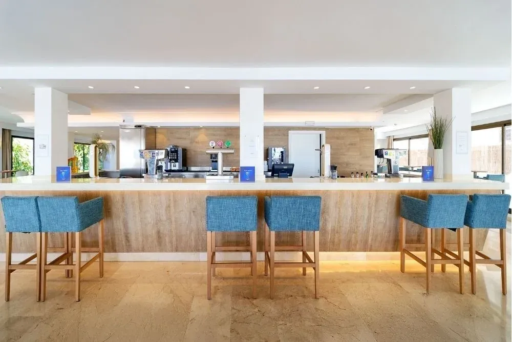 R2 Hoteles: Bar corporativo con taburetes de diseño y ambiente moderno.